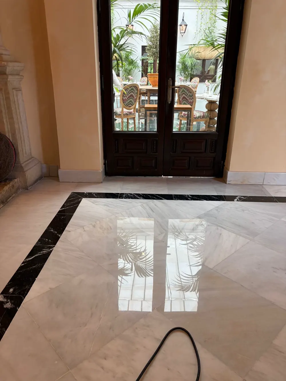 Mármol blanco con cenefa negra en hotel, reflejo de palmeras — trabajo real de Pulimentos Jiménez