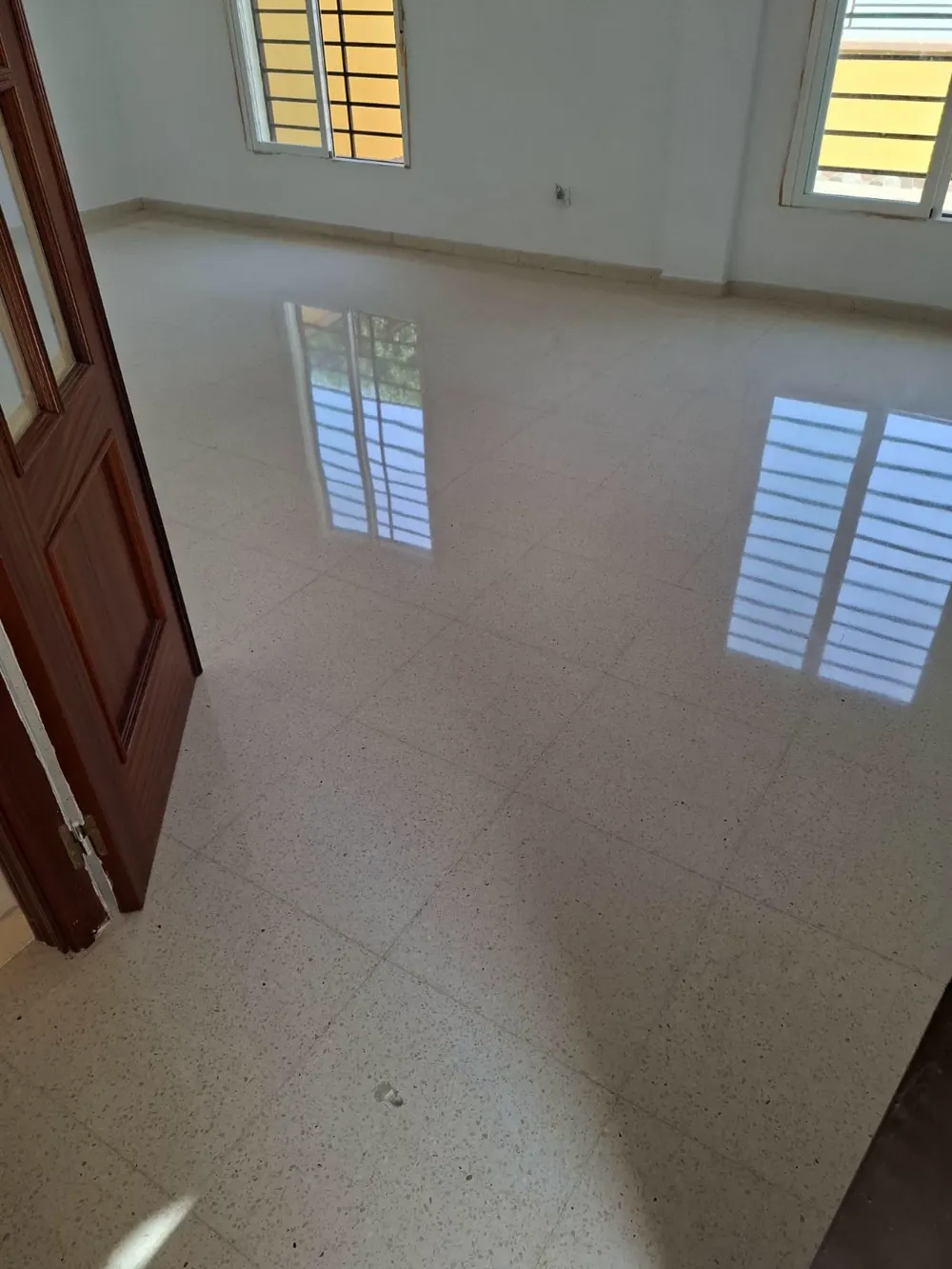 Terrazo blanco cristalizado reflejando ventanas como un espejo — trabajo real de Pulimentos Jiménez