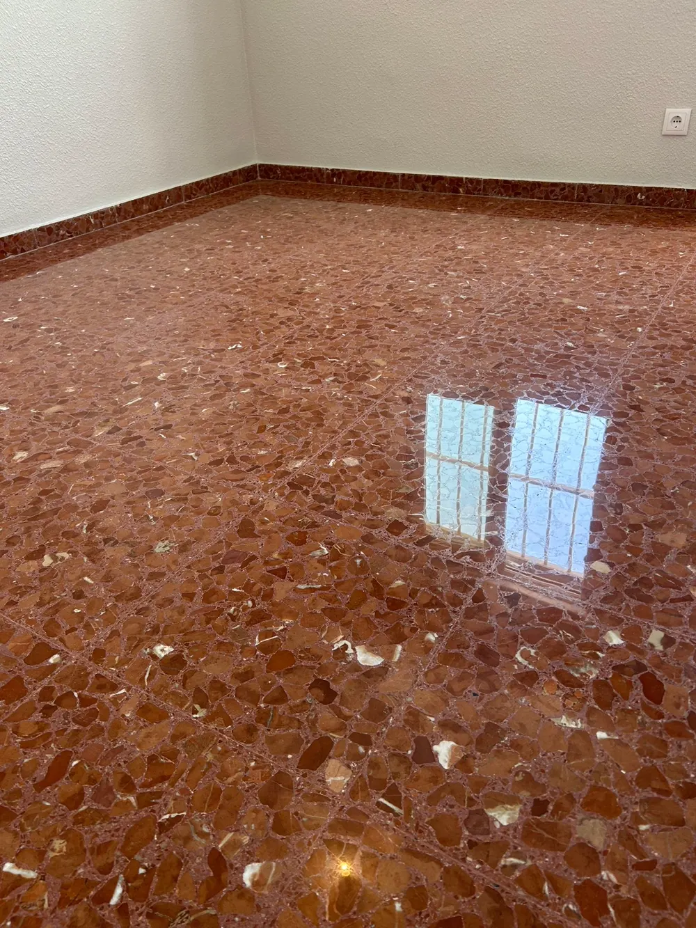 Terrazo rojo Alicante pulido espejo reflejando ventana — trabajo real de Pulimentos Jiménez
