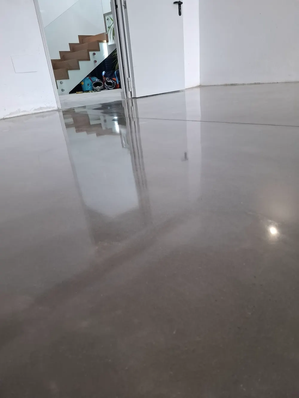 Hormigón pulido gris espejo en vivienda, escalera al fondo — trabajo real de Pulimentos Jiménez
