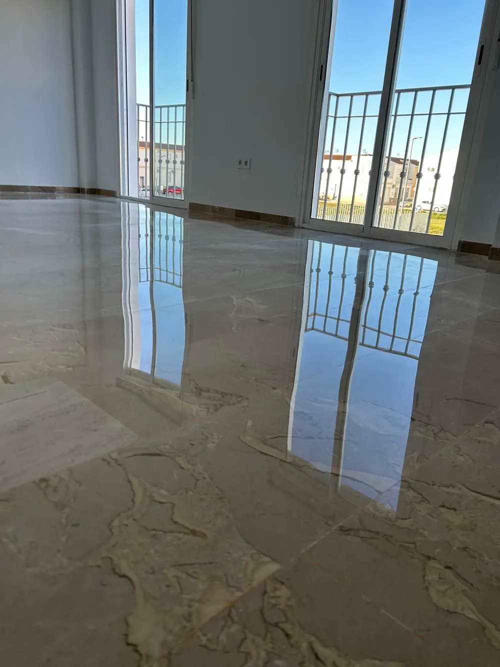 Mármol crema veteado brillo espejo reflejando balcones — trabajo real de Pulimentos Jiménez