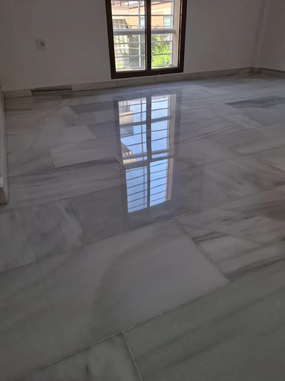 Mármol blanco grisáceo pulido reflejando la ventana — trabajo real de Pulimentos Jiménez