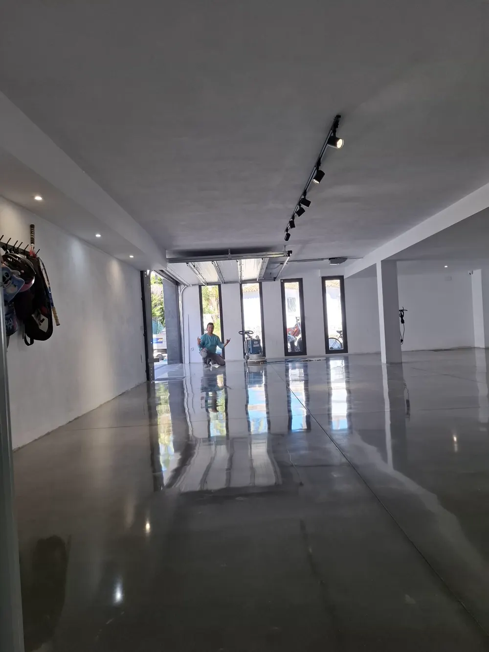 Garaje amplio brillo espejo con operario al fondo — trabajo real de Pulimentos Jiménez