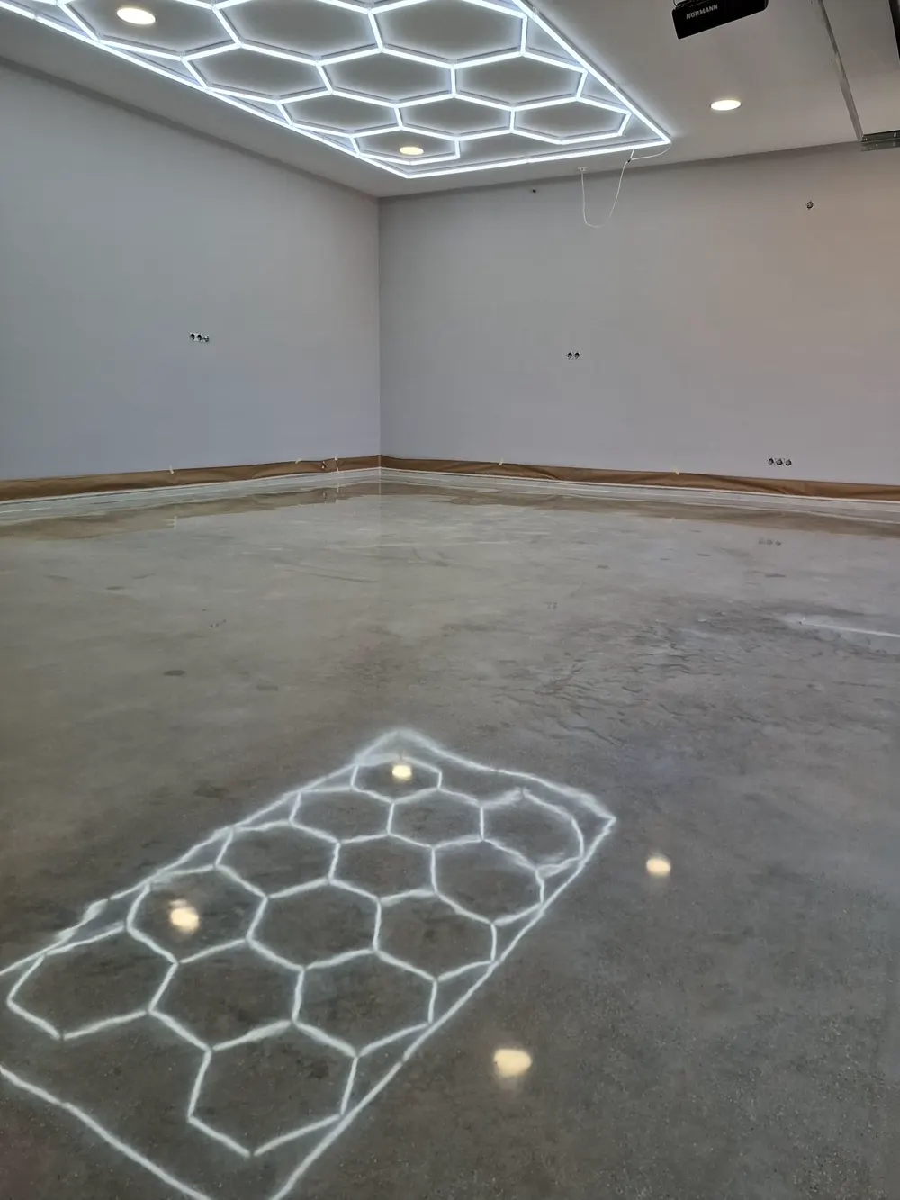 Garaje con LED hexagonal reflejado en hormigón pulido — trabajo real de Pulimentos Jiménez