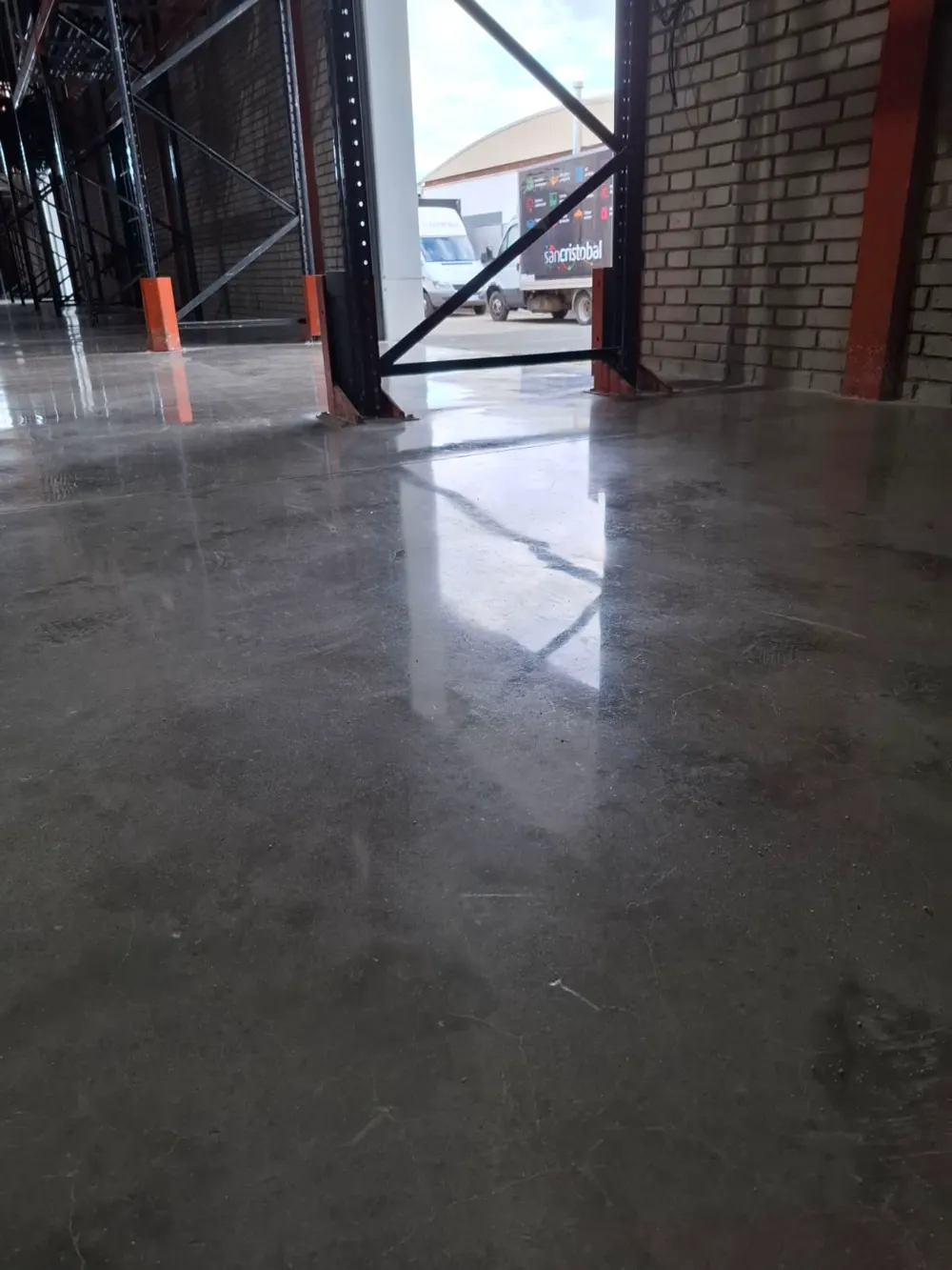 Nave con estanterías, suelo gris pulido reflectante — trabajo real de Pulimentos Jiménez