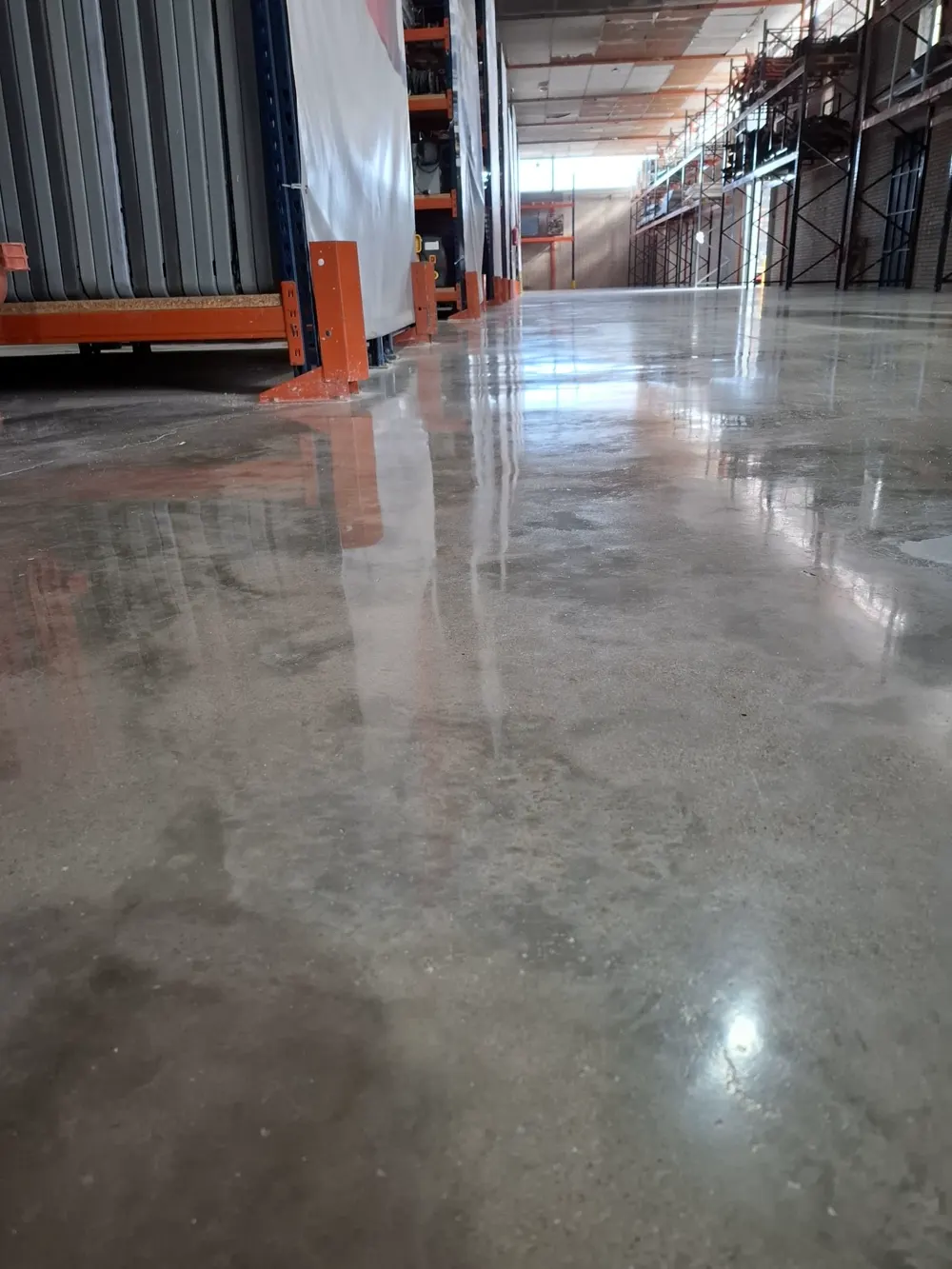 Nave industrial con estanterías y hormigón pulido brillante — trabajo real de Pulimentos Jiménez