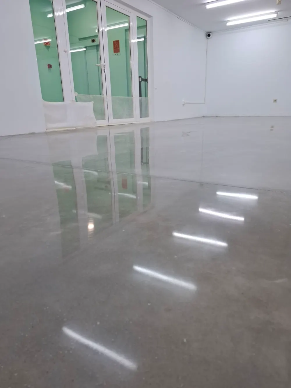 Hormigón pulido gris brillo espejo en local blanco — trabajo real de Pulimentos Jiménez