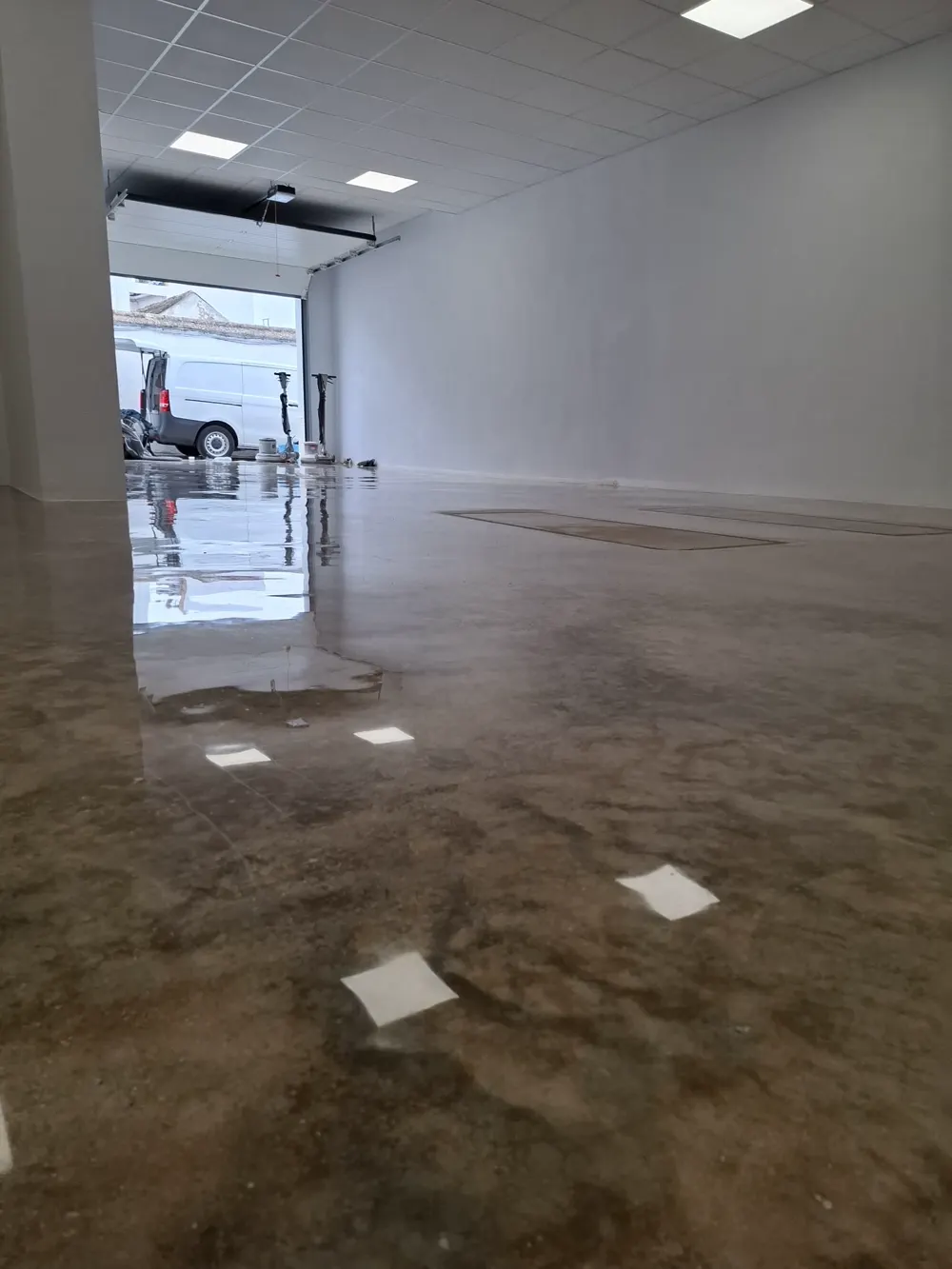Local comercial hormigón pulido espejo con furgoneta al fondo — trabajo real de Pulimentos Jiménez