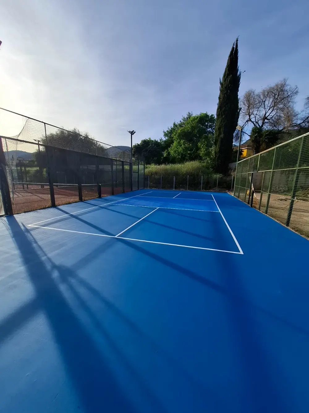 Pista de pádel azul recién pintada con líneas blancas — trabajo real de Pulimentos Jiménez