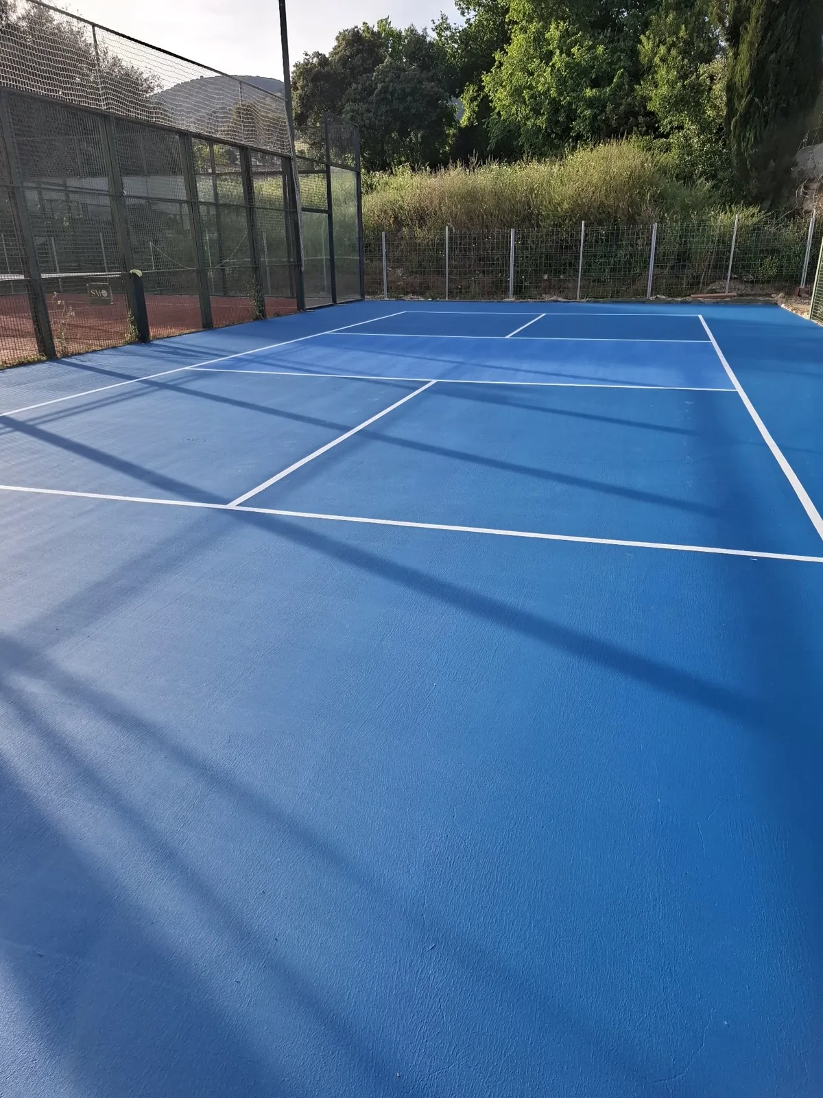 Pista deportiva azul con líneas blancas recién pintada al aire libre — trabajo real de Pulimentos Jiménez